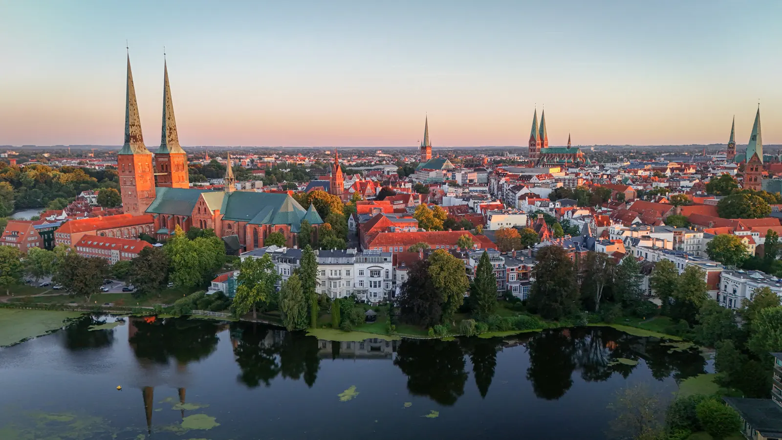 Luftaufnahme der Lübecker Altstadt im Abendlicht mit dem Dom und dem Mühlenteich im Vordergrund